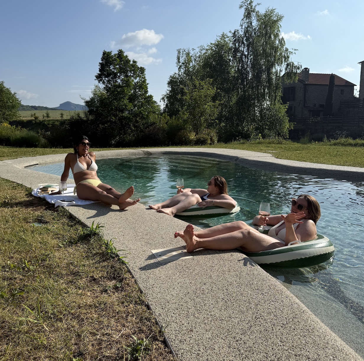 Three women chatting by the pool in the Italian countryside.
