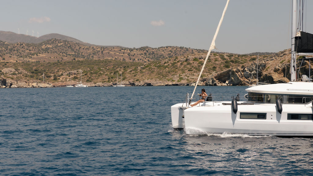 A luxury catamaran, anchored in crystal clear blue waters in Greece.