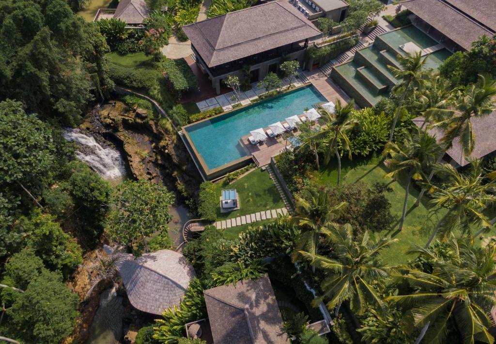 Aerial view of Nirjhara's pool and thatched pavilions surrounded by jungle and rice fields in Tabanan, Bali.