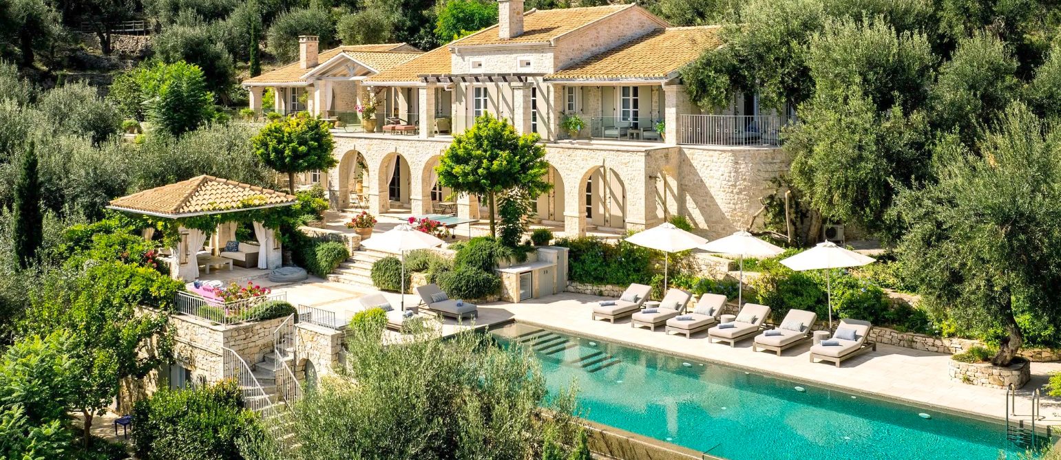 Villa Persephone's stone terraces and pool with sun loungers on Paxos, Greece.
