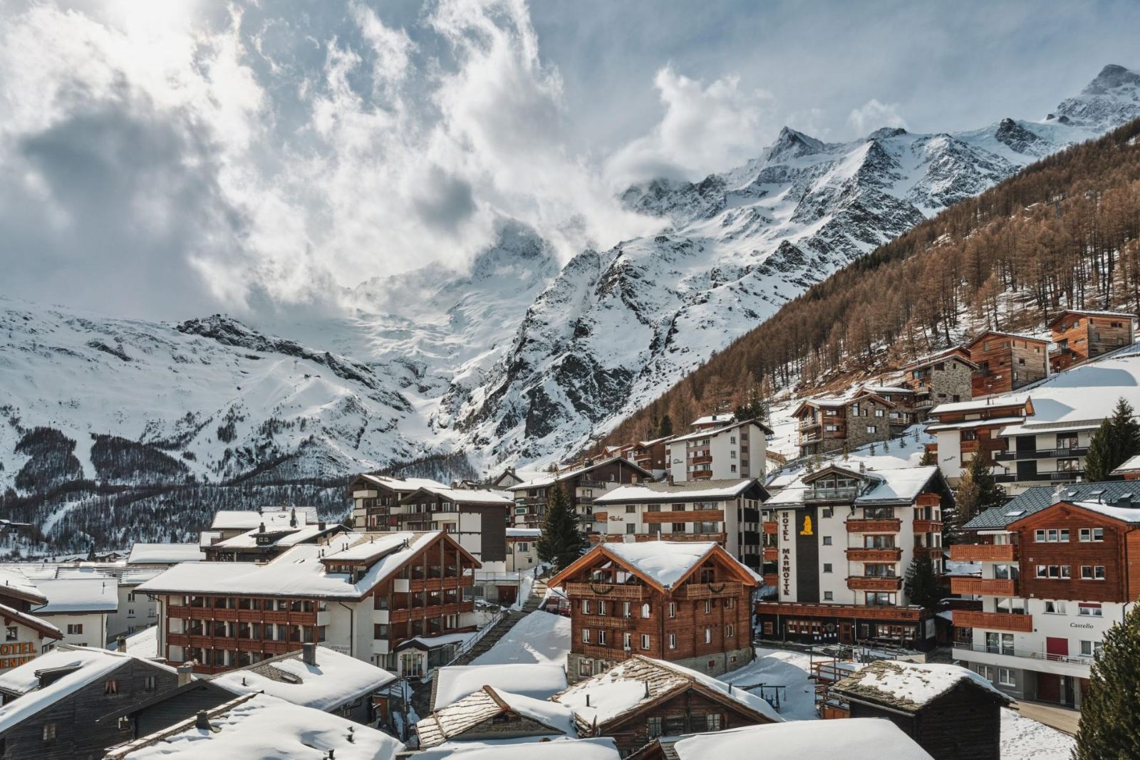 Snow-covered chalets of Saas-Fee village beneath alpine peaks in Switzerland.
