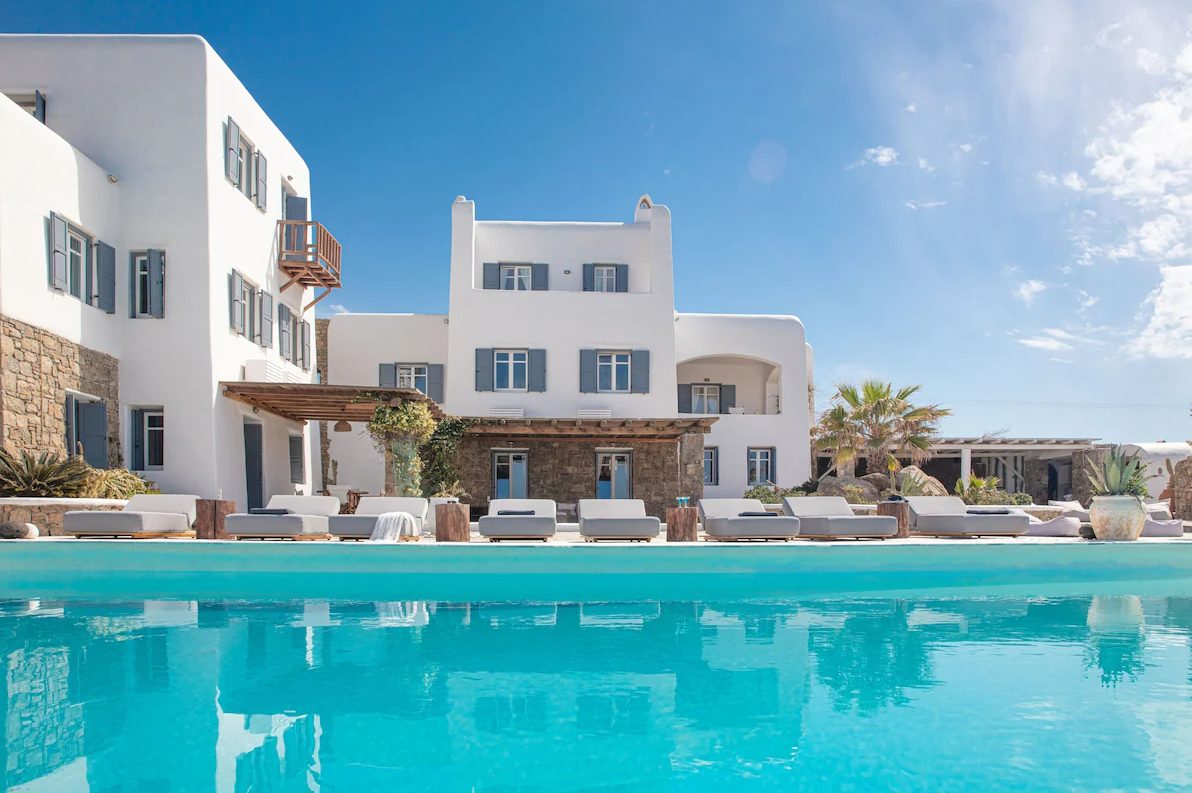 Mykonos villa with a lit pool, stone walls, and outdoor seating area.