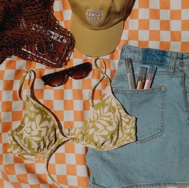 A flatlay of items packed to go on holiday against a checked blanket