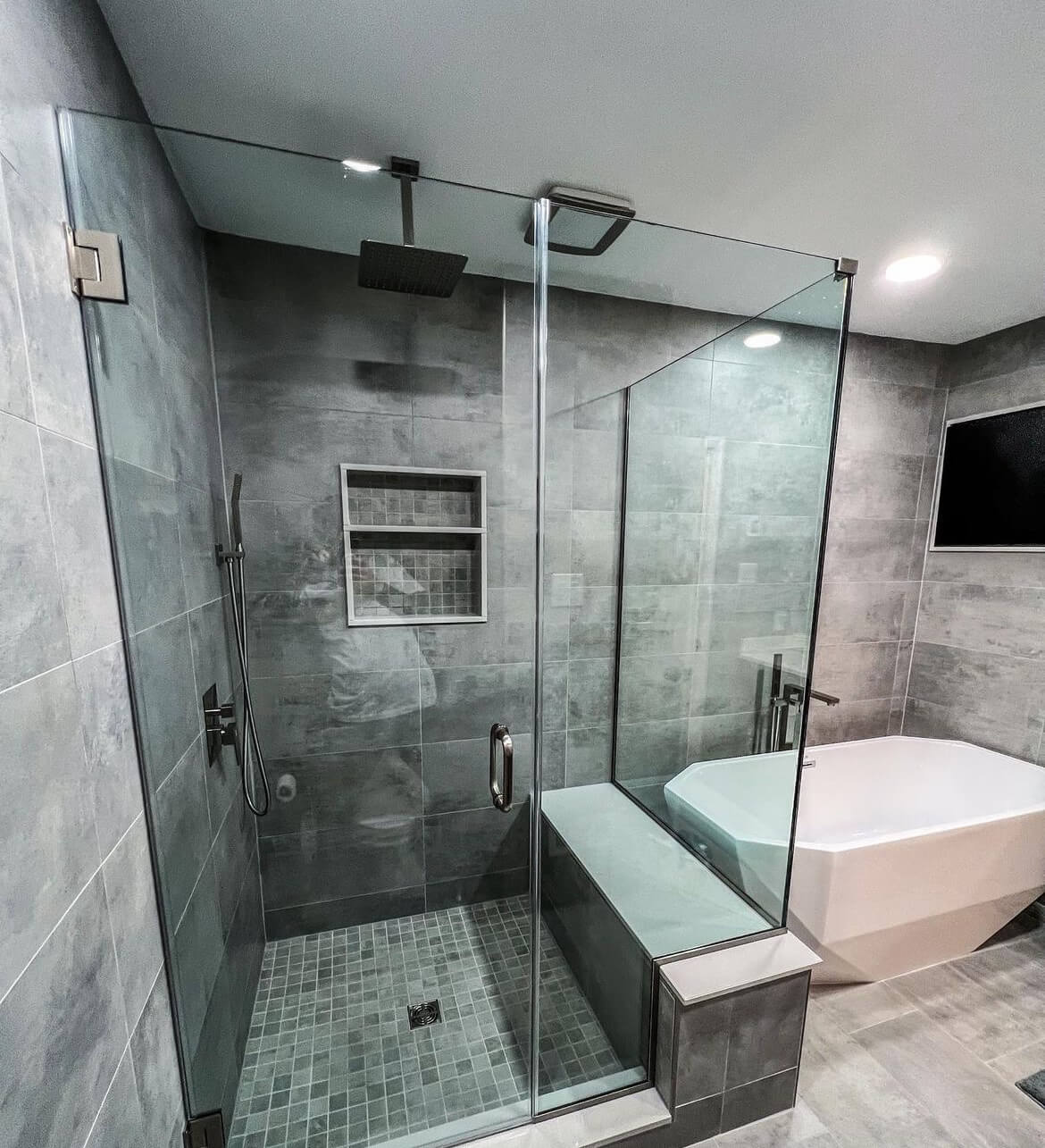 A tub and shower surround in marble look tile with matte black fixtures