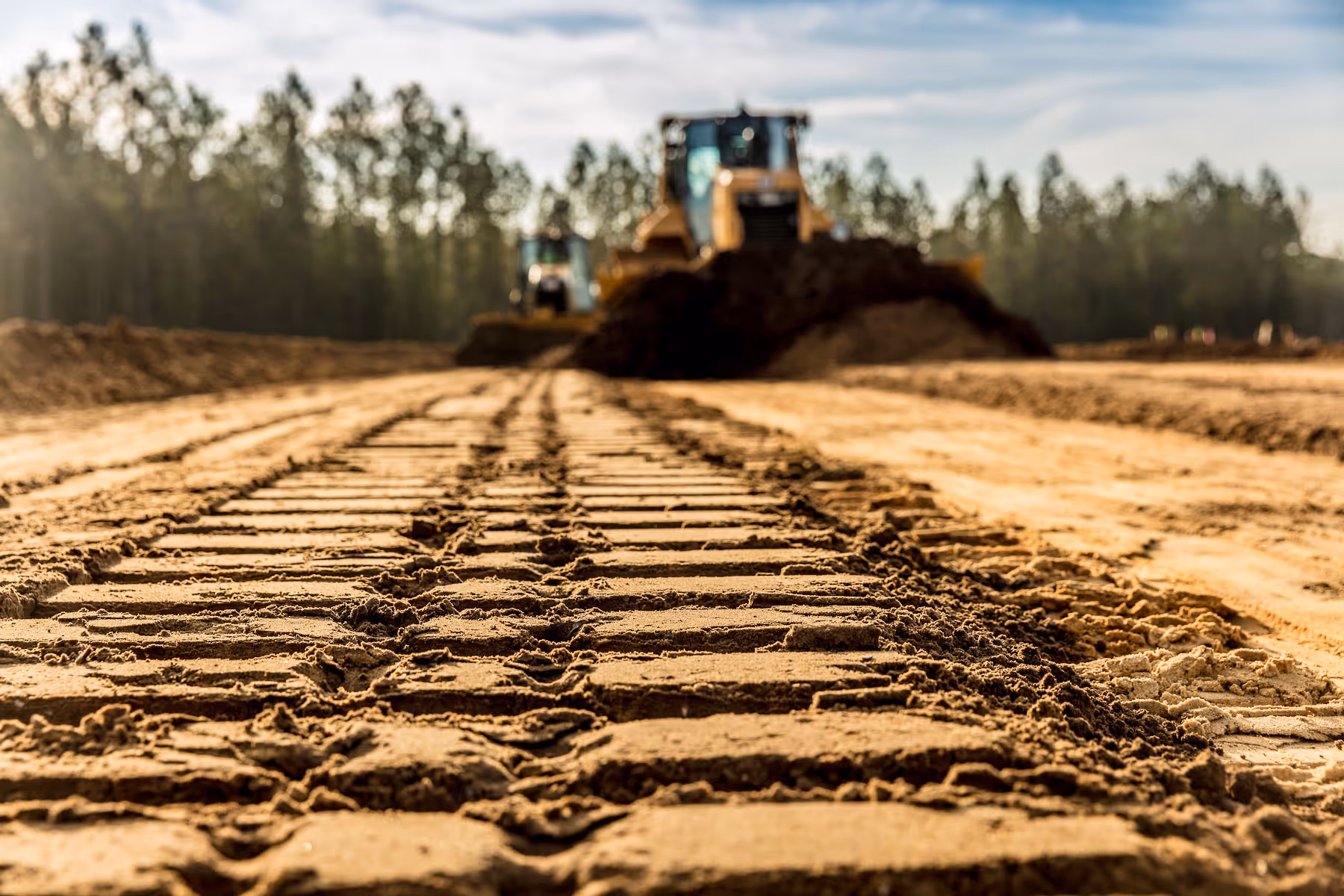 Bulldozers moving earth on construction site with forest in background