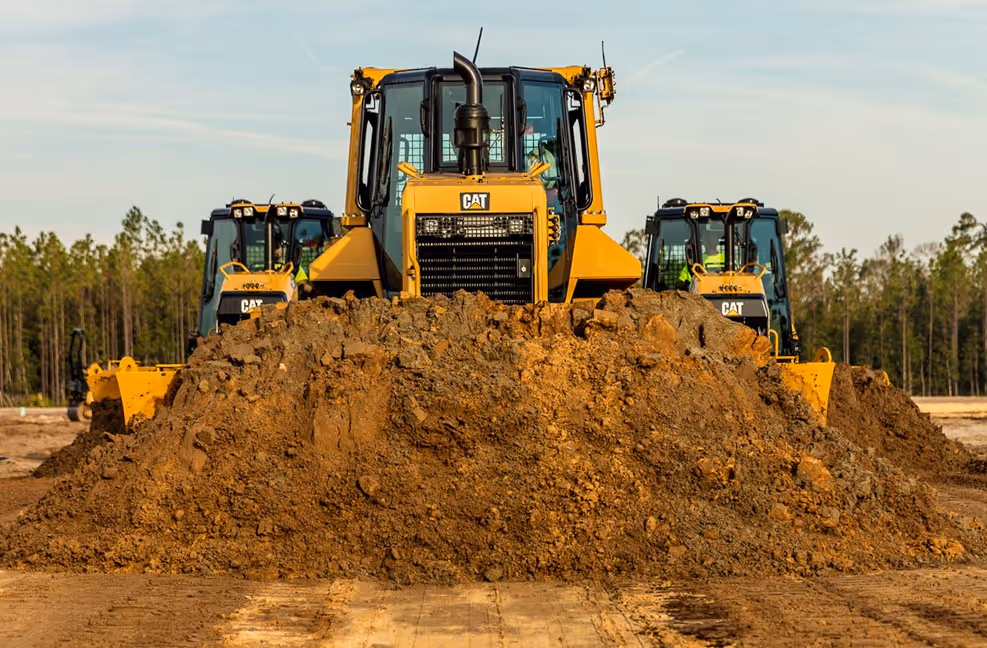 Yellow Caterpillar bulldozers lined up on a dirt construction site