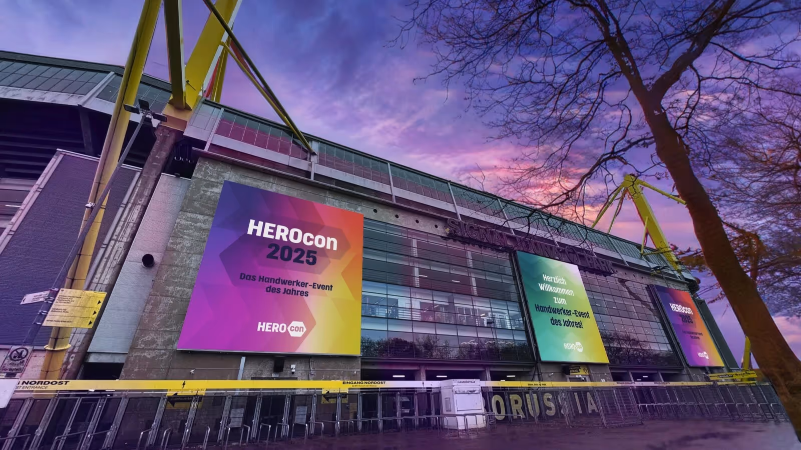 Signal Iduna Park mit großen HEROcon-2025-Bannern vor violett-pinkem Abendhimmel.
