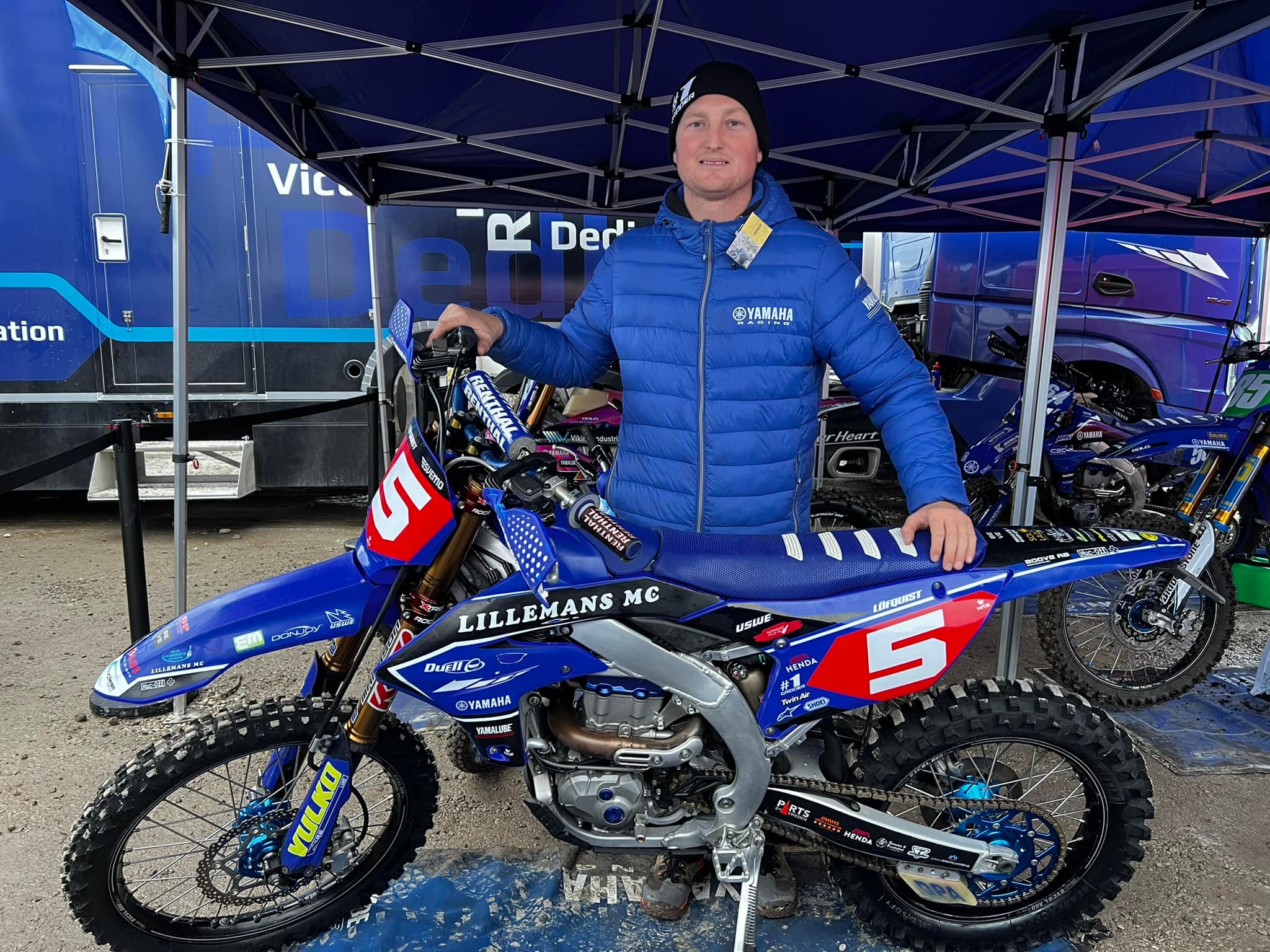 Man i blå jacka poserar bredvid en dirt bike bygg entreprenad byggservice utrustning