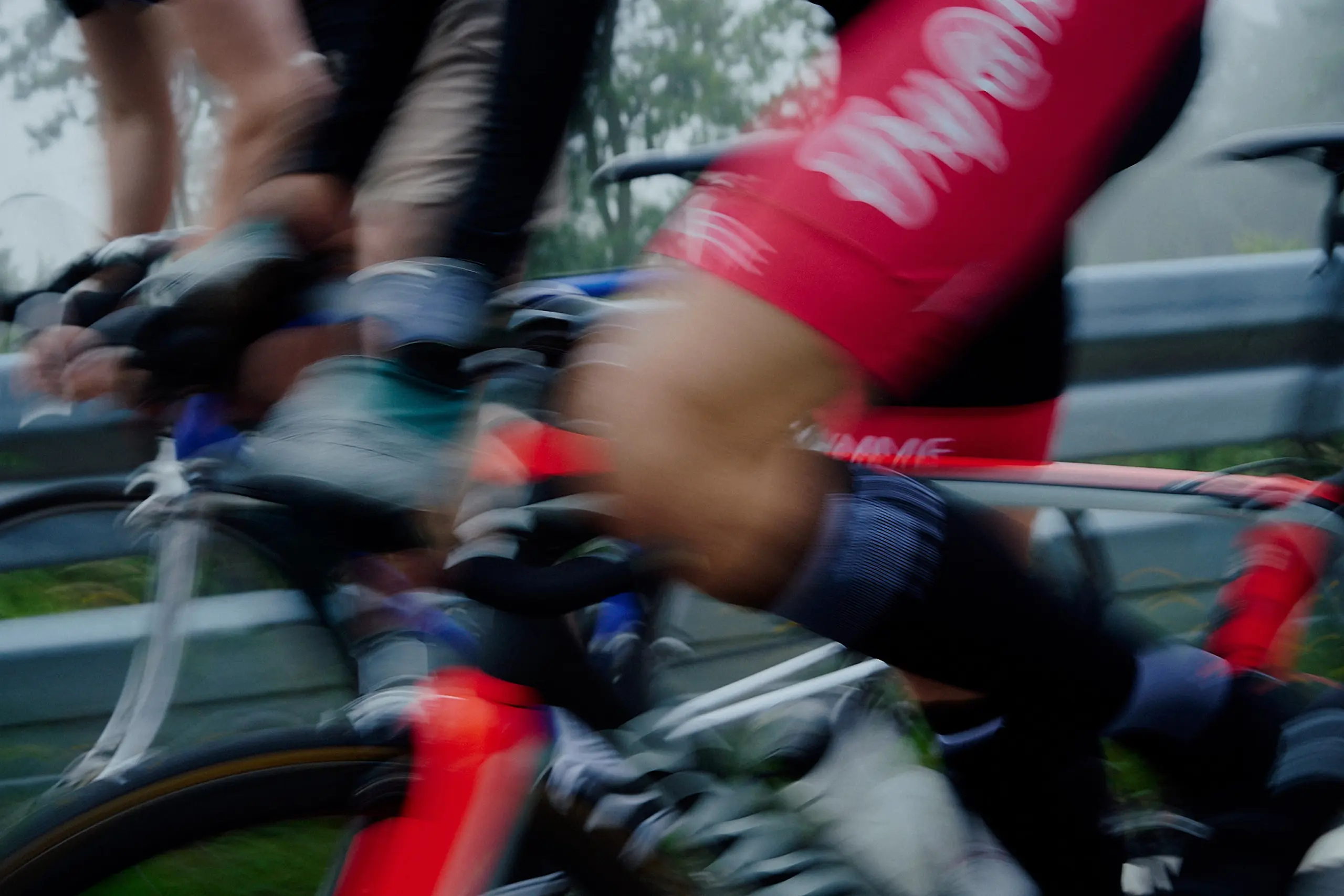Close-up of cyclists' legs in motion during a bike race, showing blurred movement and racing gear.