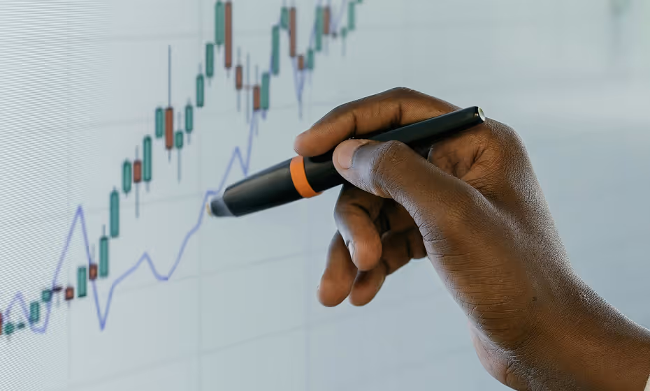 Hands holding a pen and drawing a line on a chart 