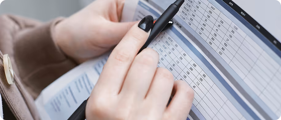 Hands holding a pen and outlining errors in a spreadsheet 