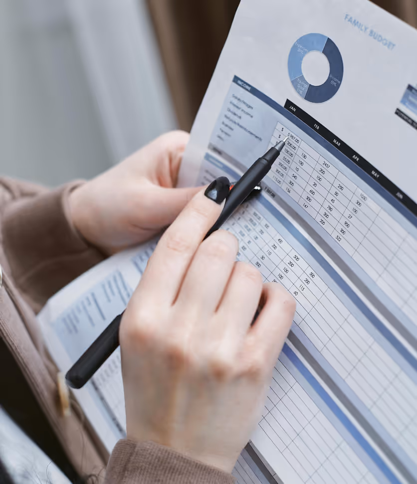 Hand holding a pen outlining inconsistencies in a spreadsheet