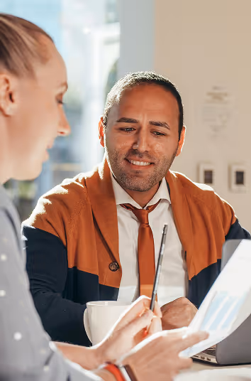 Man smiles looking at documents that a woman is presenting
