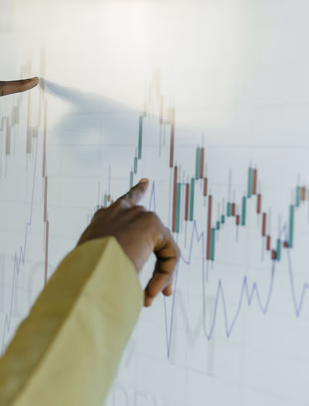 hand pointing at stock market graphs going up and down