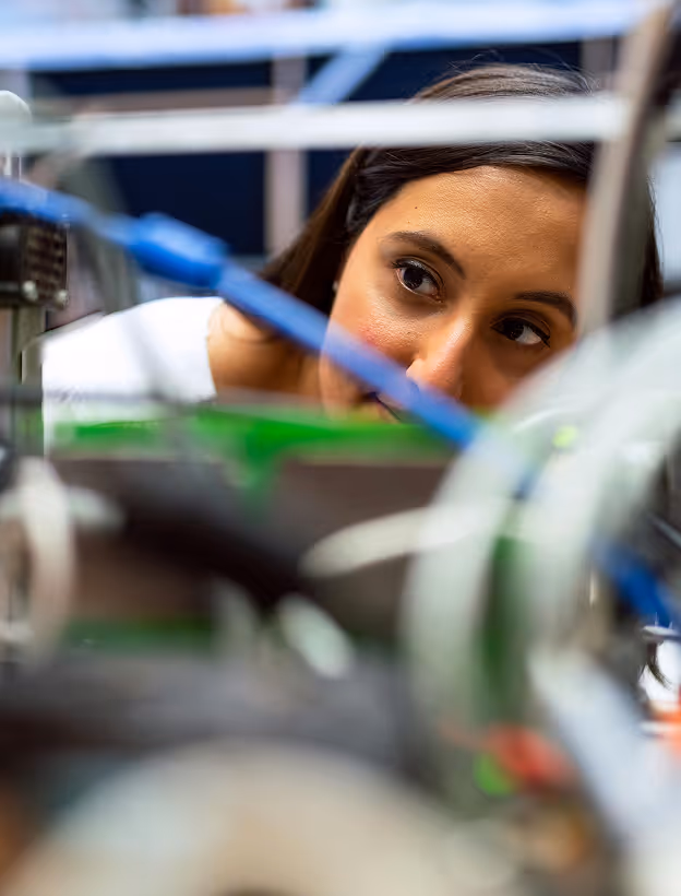 young woman looking through set up of a robot