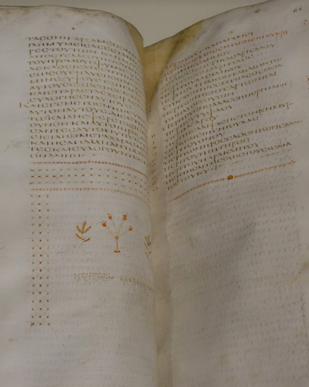 An ancient Greek manuscript Bible lies open, its pages filled with columns of capital letters.