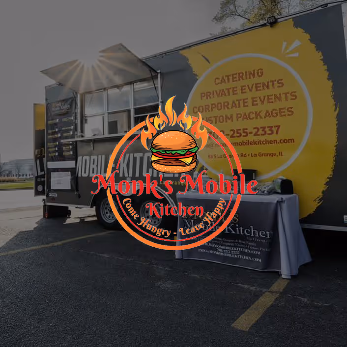 Monk's Mobile Kitchen food truck parked with a serving window open and a promotional table set up nearby.