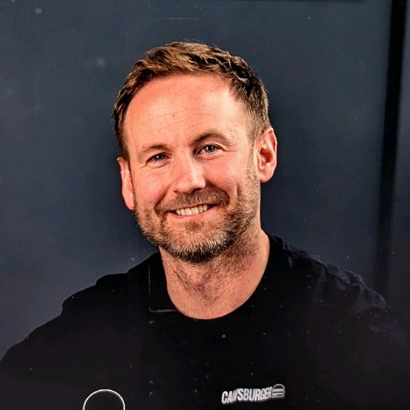 Woman with brown hair holding a copper mug cocktail in a bar setting.