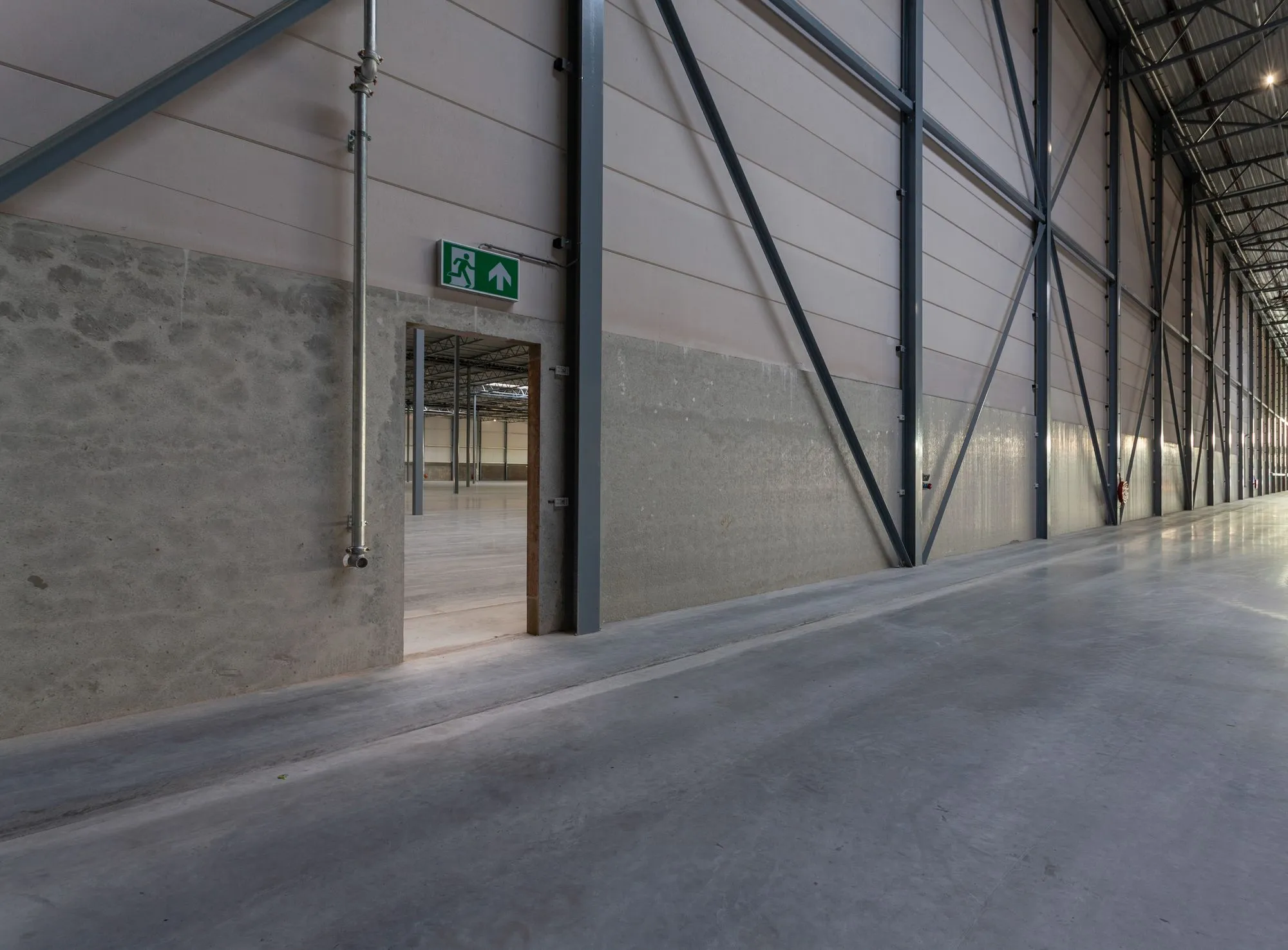 Interior de bodegas Avanza Park con letrero de salida de emergencia