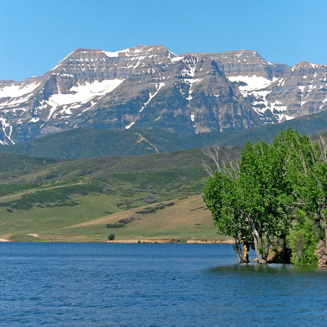 Scenic view of Mount Timpanogos and Deer Creek Reservoir near Midway, Utah, under a clear blue summer sky.