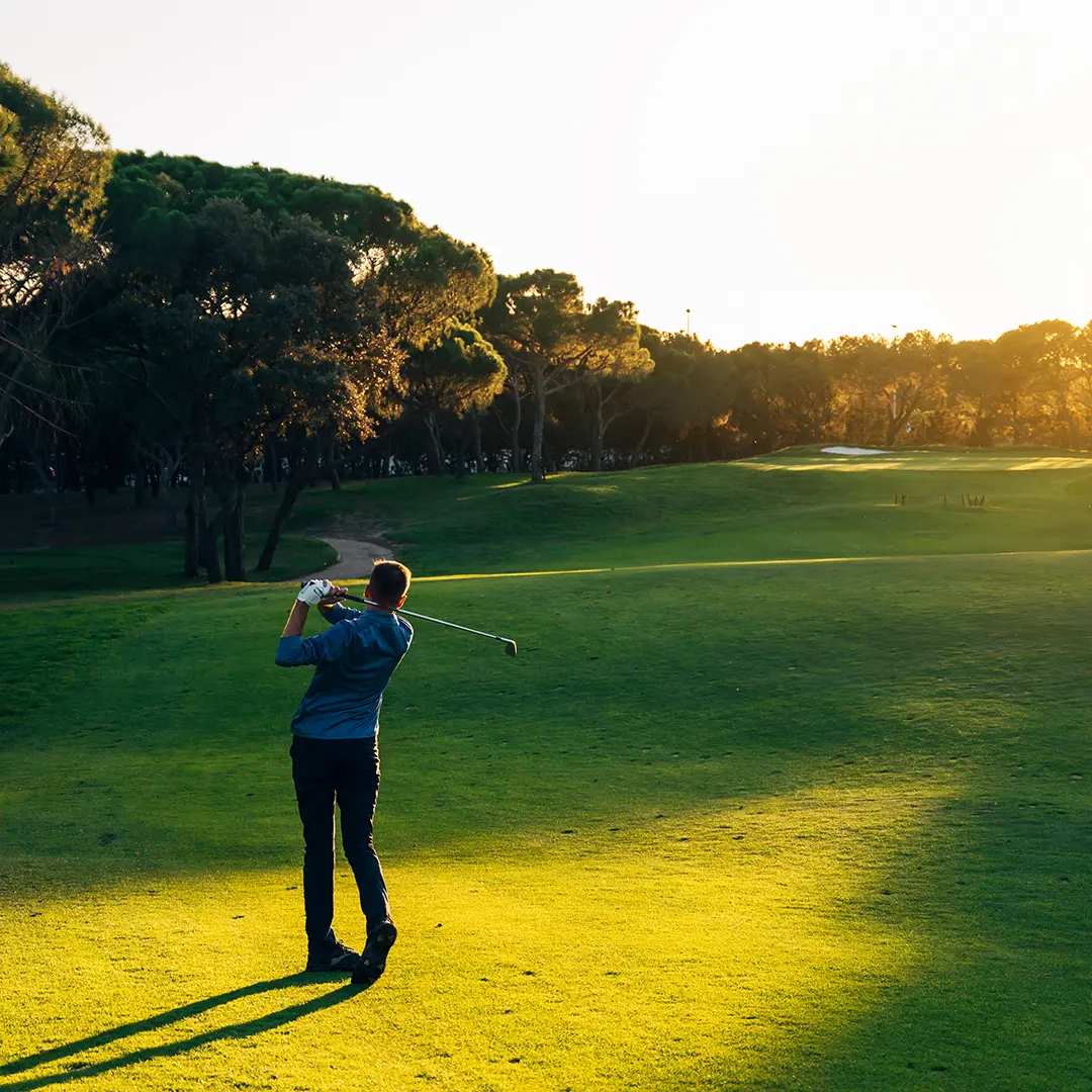 Man playing golf at sunset on a scenic course near Midway, Utah, surrounded by trees and golden light.
