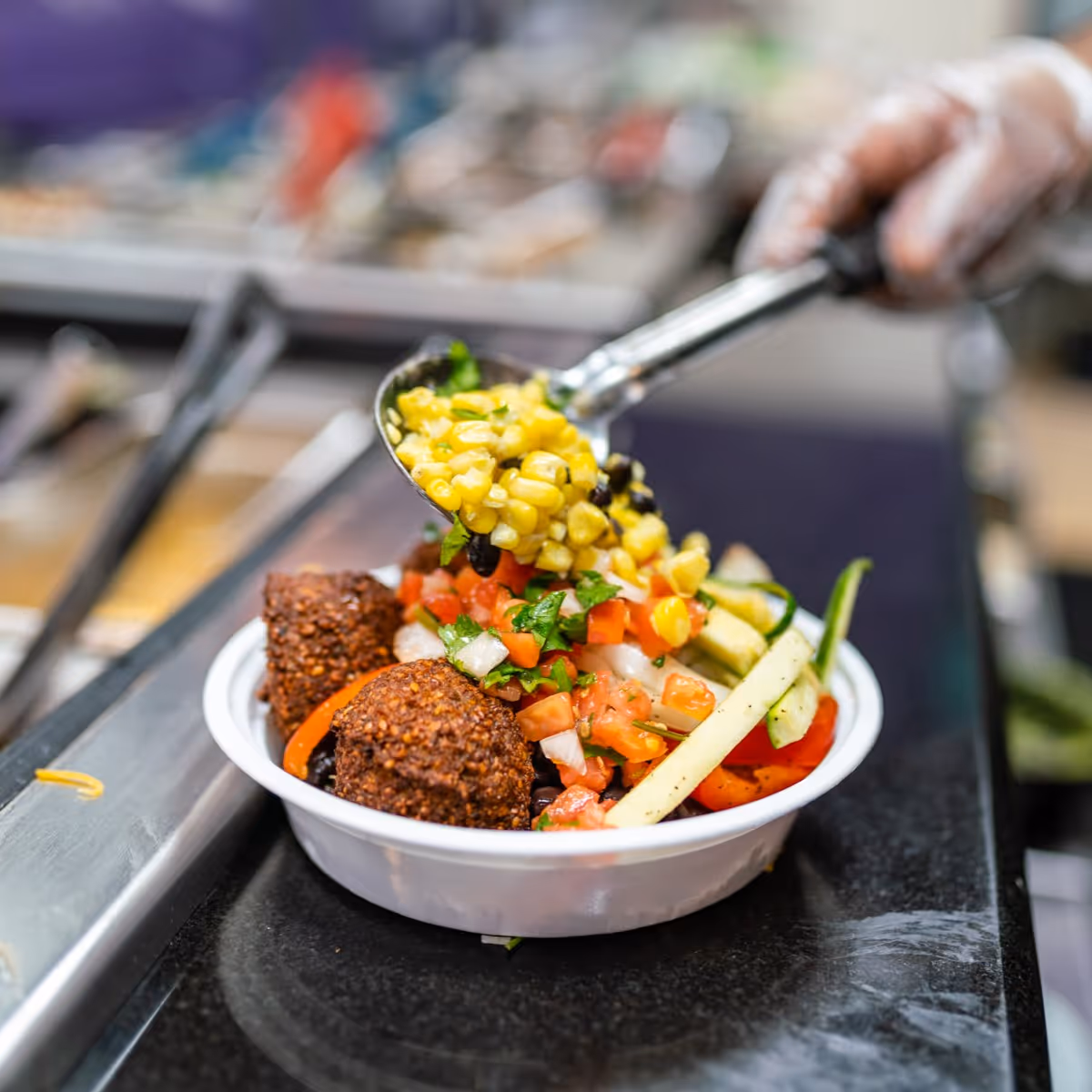 A person is holding a spoon full of food.