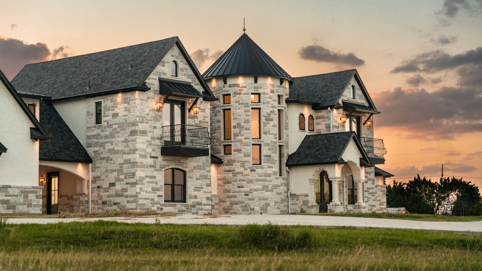 Custom-built luxury home in Liberty Hill, Texas featuring stucco exterior, stone accents, and detached casita with copper lighting.