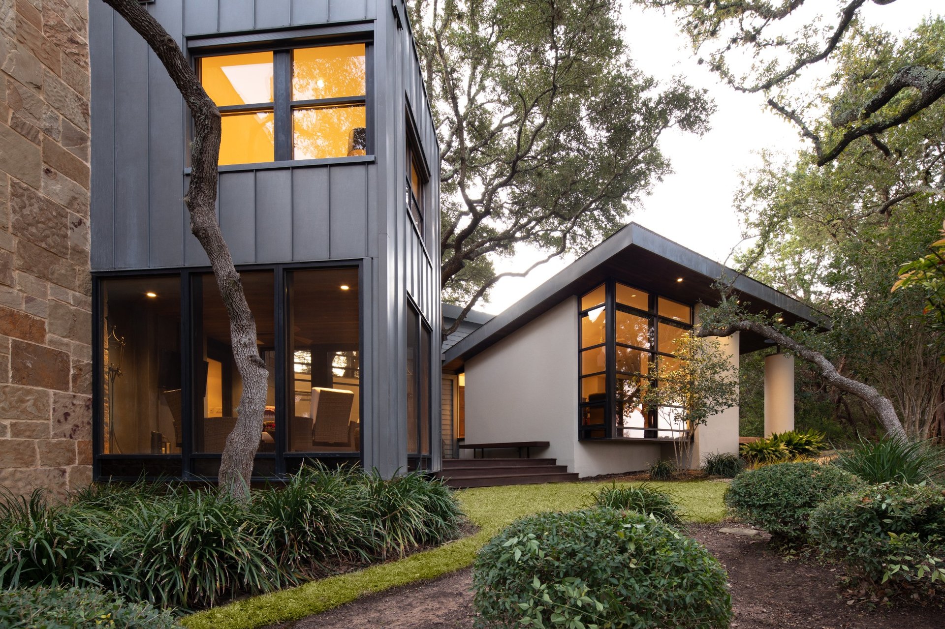 Modern Austin luxury home exterior with large windows and metal siding by River City Construction and Design.
