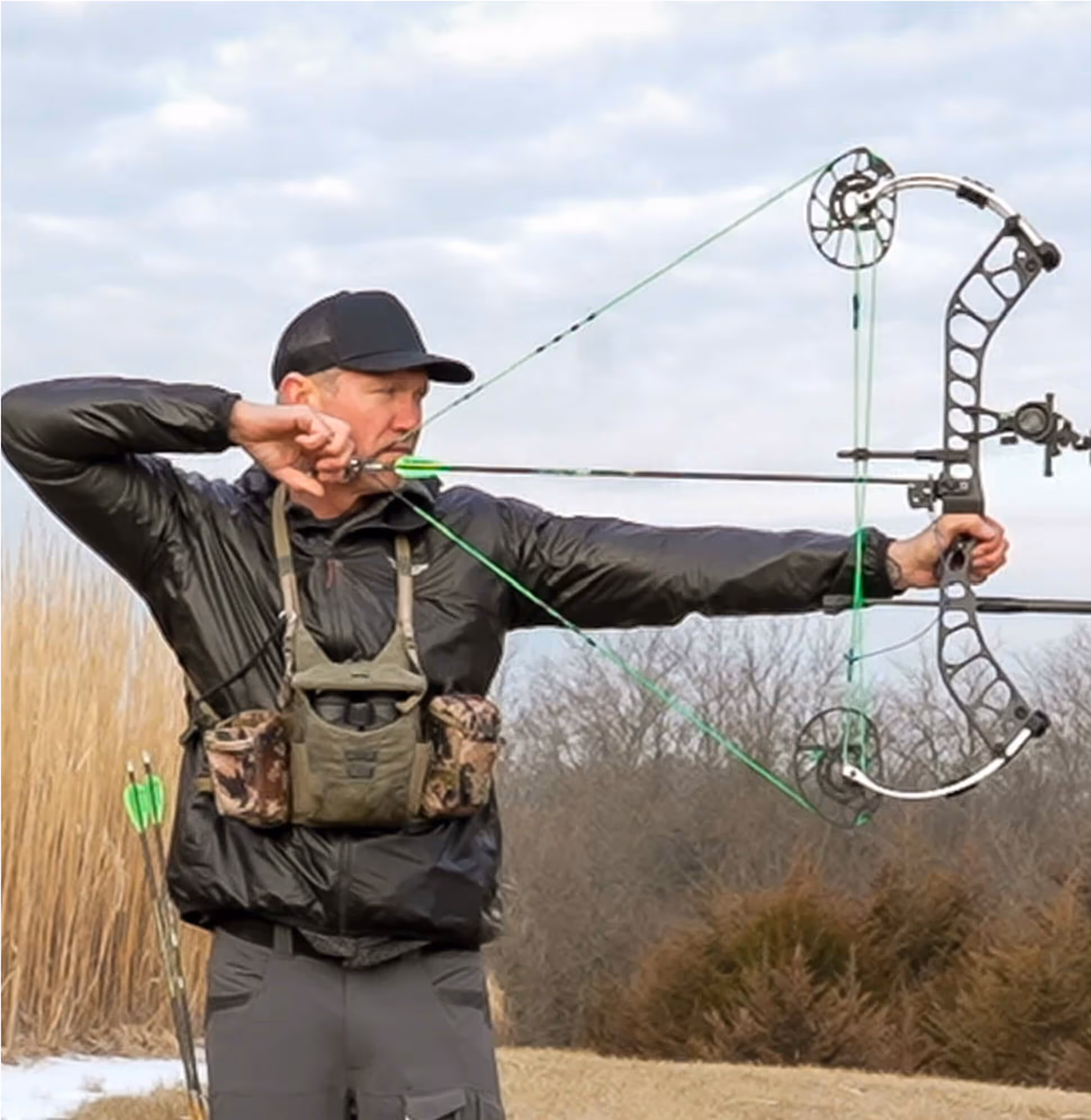 Man firing a bow&arrow, wearing Sitka hunting gear.