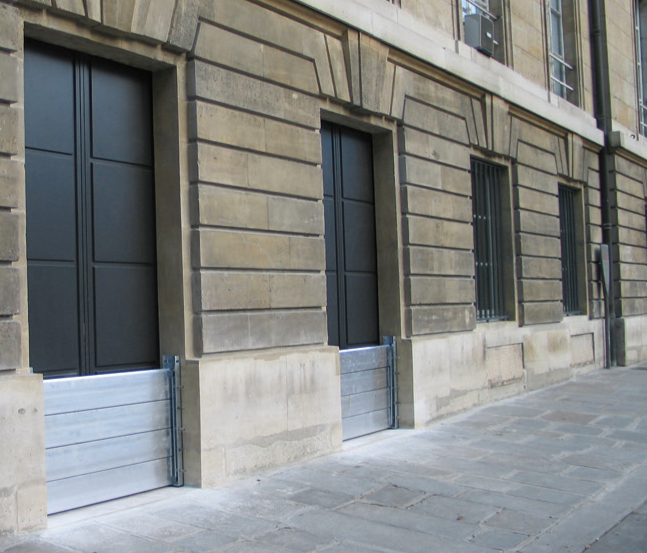 Barrières anti-inondation entre deux murs pour protéger des portes d'entrée d'immeubles hausmannien