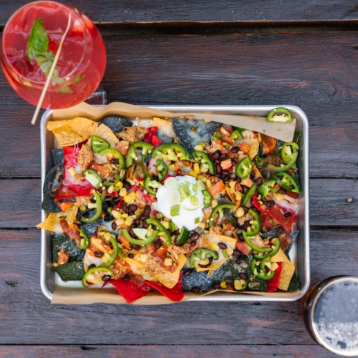 A top down photo of nachos on a table with a cocktail
