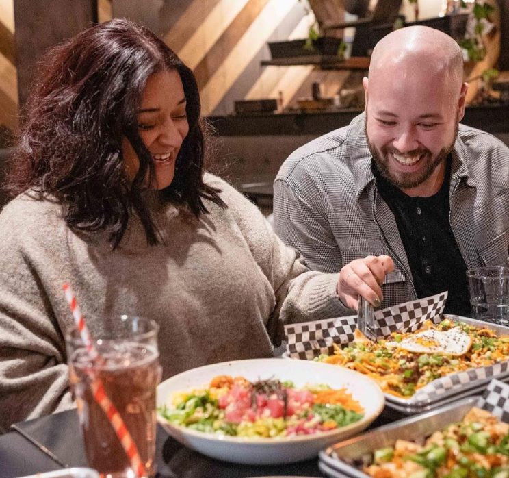 Two happy customers sharing a plate of craft nachos