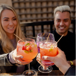 A table smiling and enjoying each other's company over some colorful cocktails
