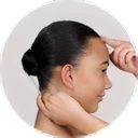 Profile of a woman with dark hair styled in a bun, holding her neck and forehead.