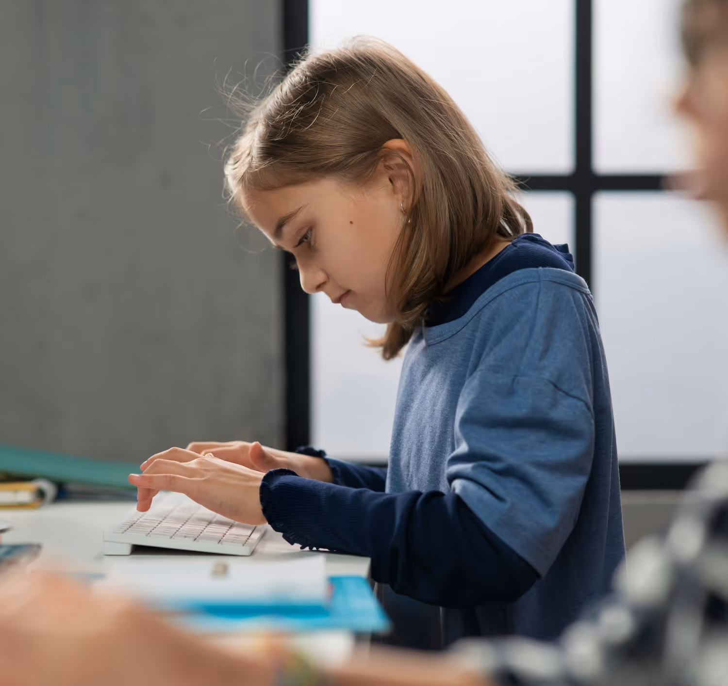 Teacher guiding a young student with tablet in a classroom.