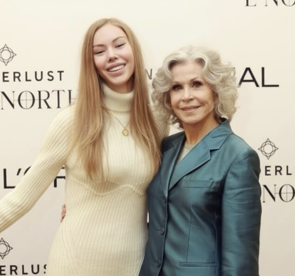 Two smiling women, Sarah Marks who has long blonde hair in a cream sweater dress, with Jane Fonda who has curly gray hair in a teal jacket.
