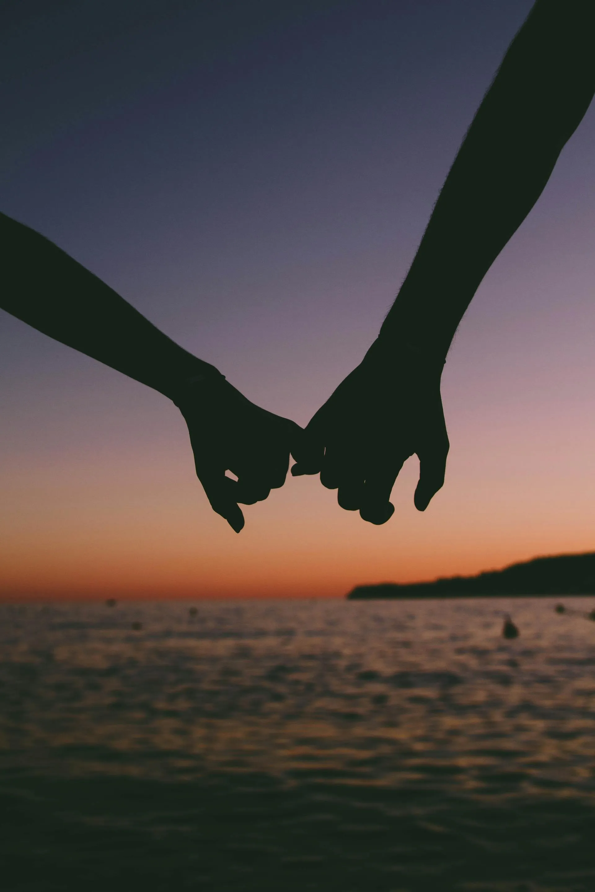 Two people holding hands at sunset