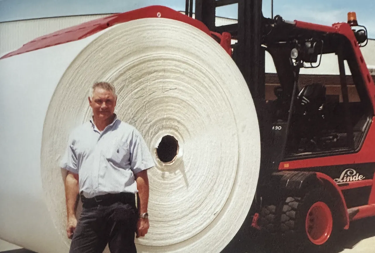 David standing next to a jumbo roll of paper at Encore Tissue