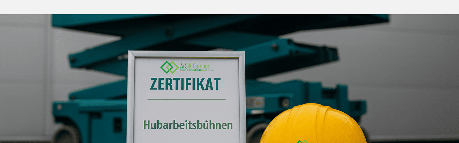 Hubarbeitsbüühne im Hintergrund. Im Vordergrund ein Zertifikat Hubarbeitsbühnen mit einem helm auf der rechten seite daneben