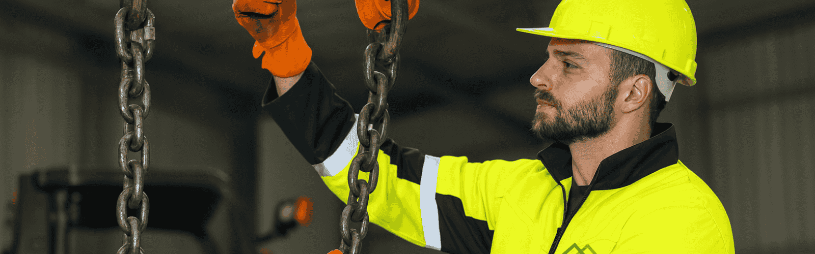 Mann mit Sicherhetiskleidung macht gerade eine Anschlagskette ein einen Stahlträger