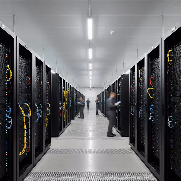 Data center aisle with multiple server racks and technicians working on equipment.