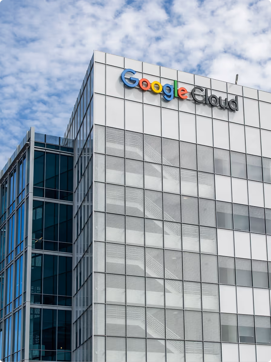 Modern office building with Google Cloud logo on the upper corner against a partly cloudy sky.