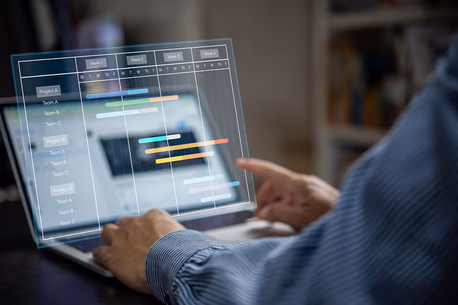 Person interacting with a laptop displaying a transparent digital Gantt chart showing project timelines for multiple teams over four weeks.