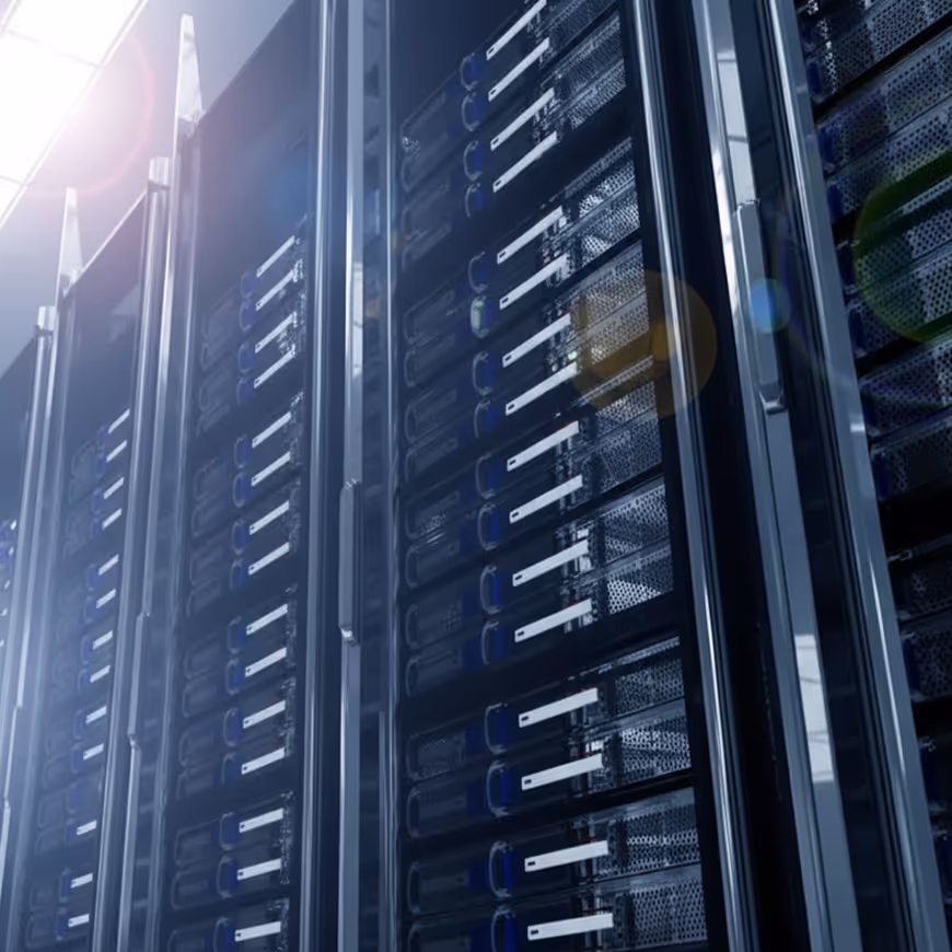 Row of black server racks with multiple server units in a data center, illuminated by bright light.