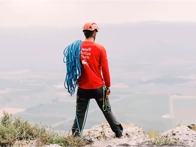 A man stands looking to the view, with search and rescue equipment and uniform.