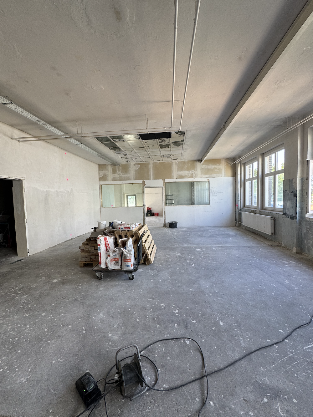 Baustelle in Innenräumen mit losem Baumaterial und offenem Deckenbereich.