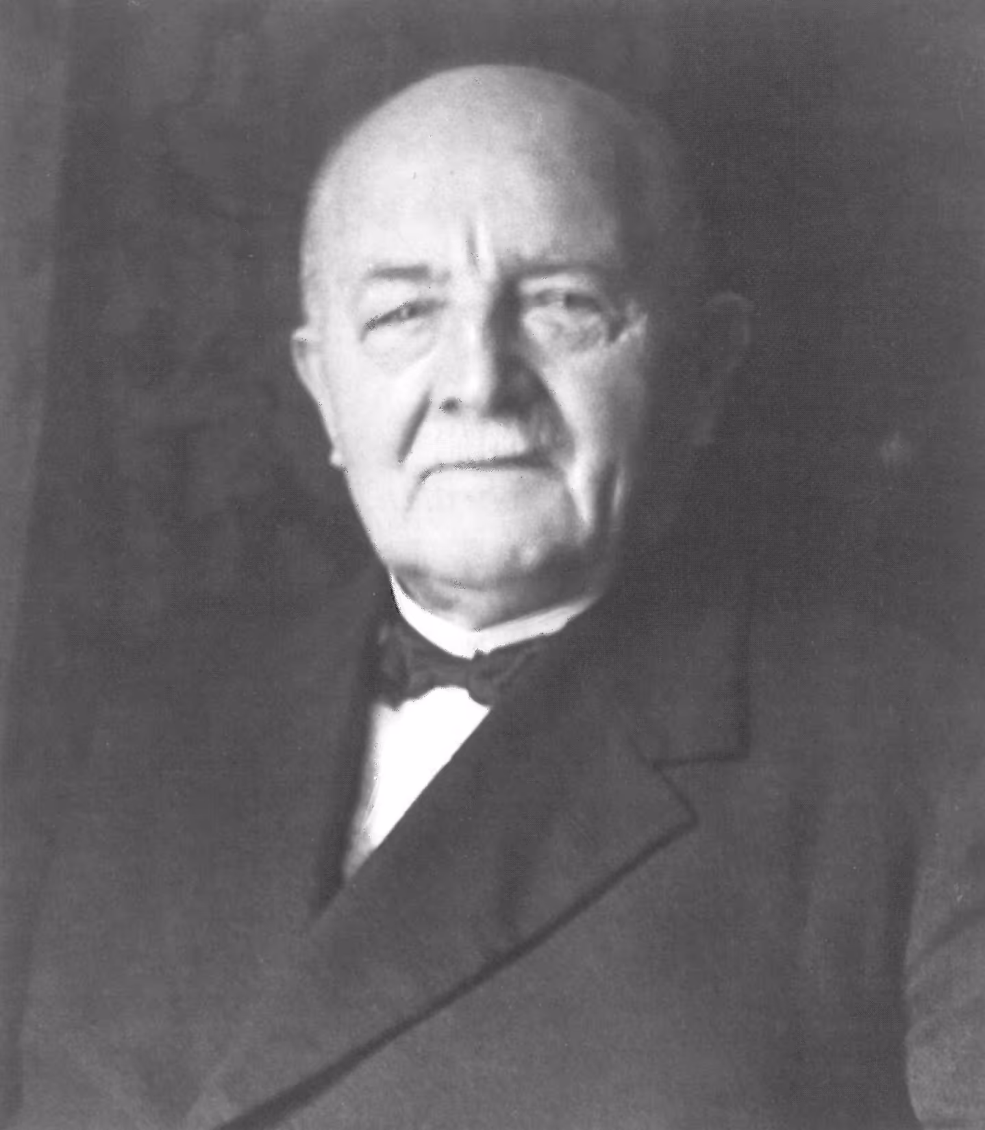 Schwarzweiß-Porträt von Schmiedemeister Heinrich Schmidt, Firmengründer, mit Anzug und Fliege.