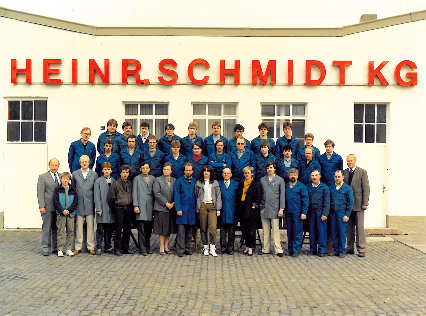 Gruppenfoto der Belegschaft der Heinr. Schmidt KG vor dem Firmengebäude in Paderborn, aufgenommen um 1985.