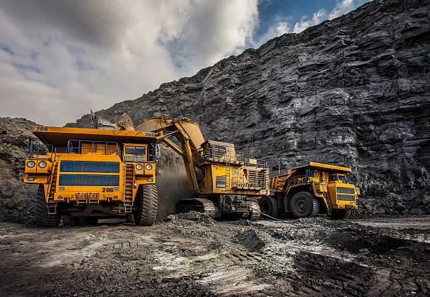 Large yellow mining trucks and an excavator working at a rocky mining site.