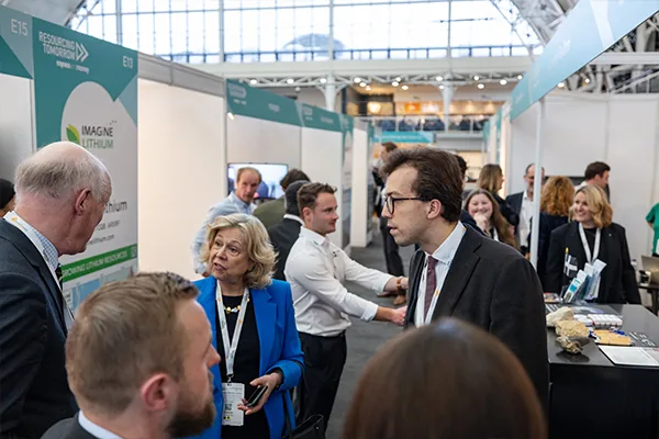 A busy trade show or convention with people networking and talking at various exhibition booths.